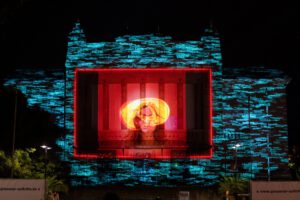 Ein Video wird auf eine große Theater Hauswand gestrahlt.
